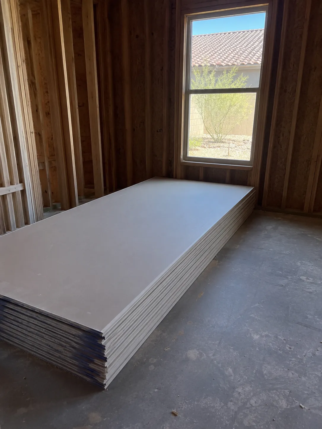 Stack of drywall sheets delivered in an empty room ready for installation