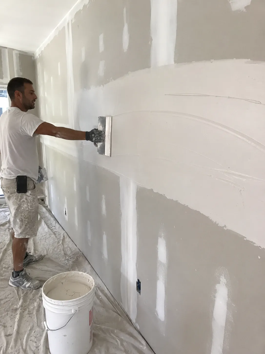 Drywall finisher spreading joint compound across a wall